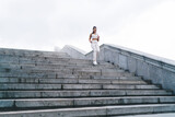 Slim Hispanic sportswoman running downstairs during training on street
