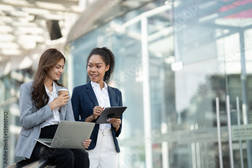 Two Asian businesswomen discussing business information while standing outside the office. Free Download Two Asian businesswomen discussing business information while standing outside the office. - GFXLoad