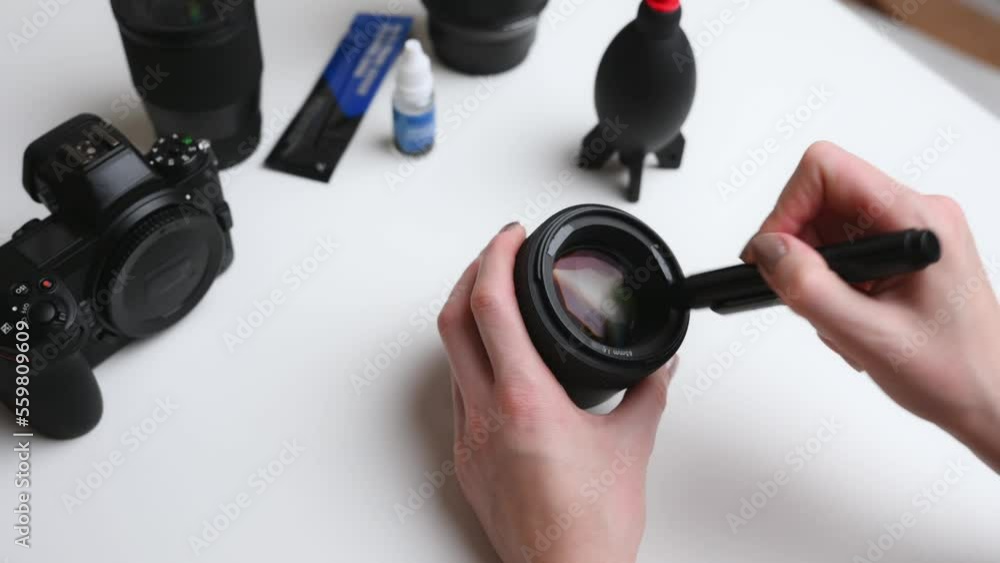 Cleaning the lens of a digital camera from dust with a special cleaning brush. The concept of caring for photographic equipment, cleaning the camera lens. The photographer cleans the lens. Cleaning the lens of a digital camera from dust with a special cleaning brush. The concept of caring for photographic equipment, cleaning the camera lens. The photographer cleans the lens.