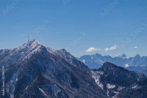 Scenic view of snow capped mountain peak Dobratsch, Julian Alps and the Karawanks (Karawanken) seen from Kobesnock in Bad Bleiberg, Carinthia, Austria, Europe. Winter wonderland landscape on sunny day