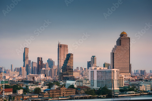 Cityscape of skyscraper building and traditional village on waterfront in Bangkok downtown at evening