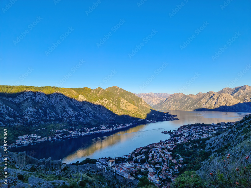 Fototapeta premium Panoramic view of the bay of Kotor during sunrise in summer, Adriatic Mediterranean Sea, Montenegro, Balkan Peninsula, Europe. Fjord winding along the coastal towns. Lovcen and Orjen mountain range