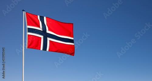 Norwegische Nationalflagge im Wind wehend vor blauem Himmel