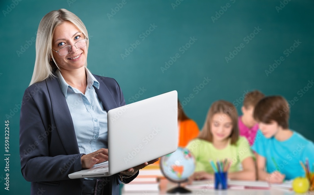 Happy young teacher in class with schoolchild on background. Happy young teacher in class with schoolchild on background.
