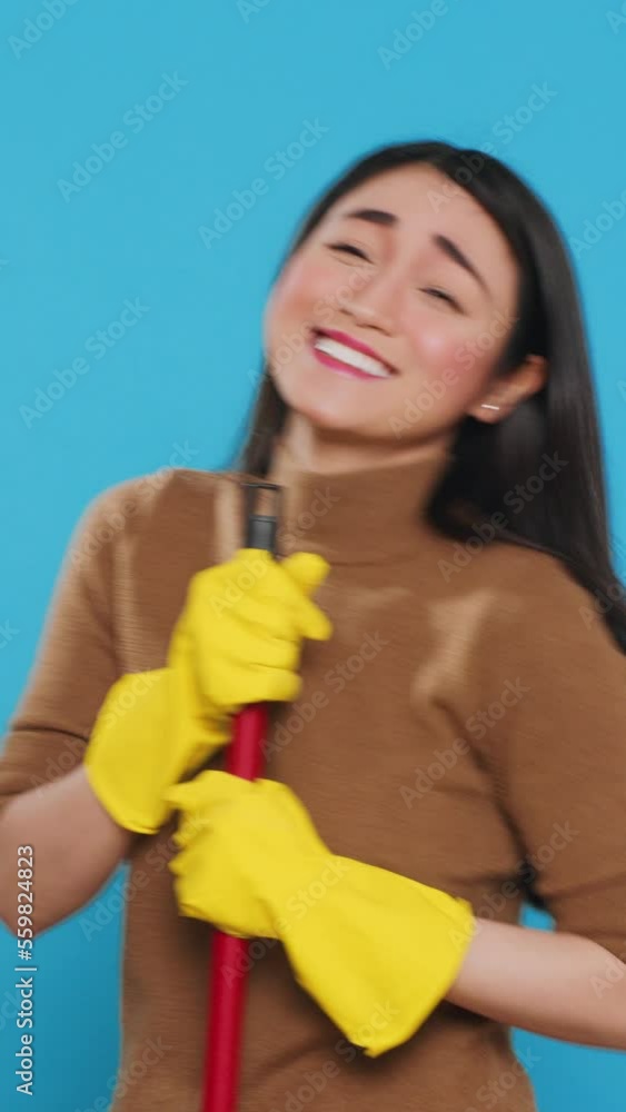 Vertical video: Happy housekepper dancing and having fun in studio while doing housecleaning using broom, dedicated to providing top-notch cleaning services to her clients. Housekeeping concept. Vertical video: Happy housekepper dancing and having fun in studio while doing housecleaning using broom, dedicated to providing top-notch cleaning services to her clients. Housekeeping concept.