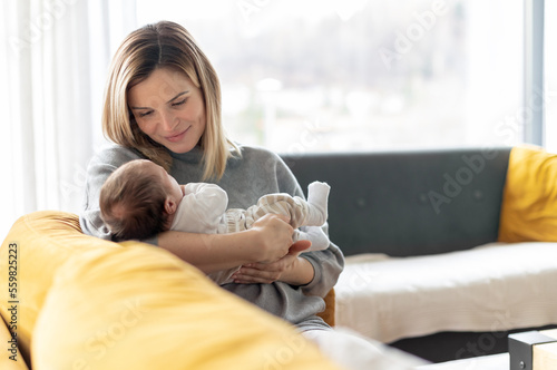 Loving mother hugs her little baby at home on sofa