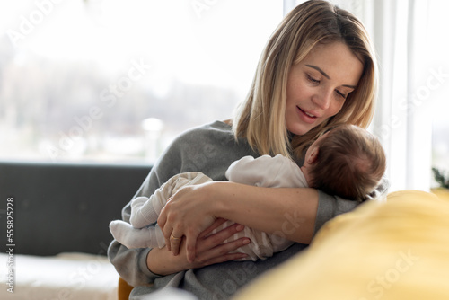 Obraz na płótnie Loving mother hugs her little baby at home on sofa