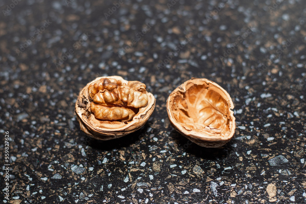 A ripe open walnut in its shell on a black table A ripe open walnut in its shell on a black table