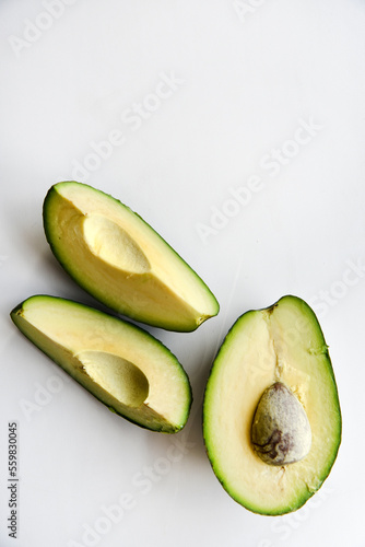 Green avocado fruit cut into slices on a white background. Avocado on a white plate. Avocado slices and halves
