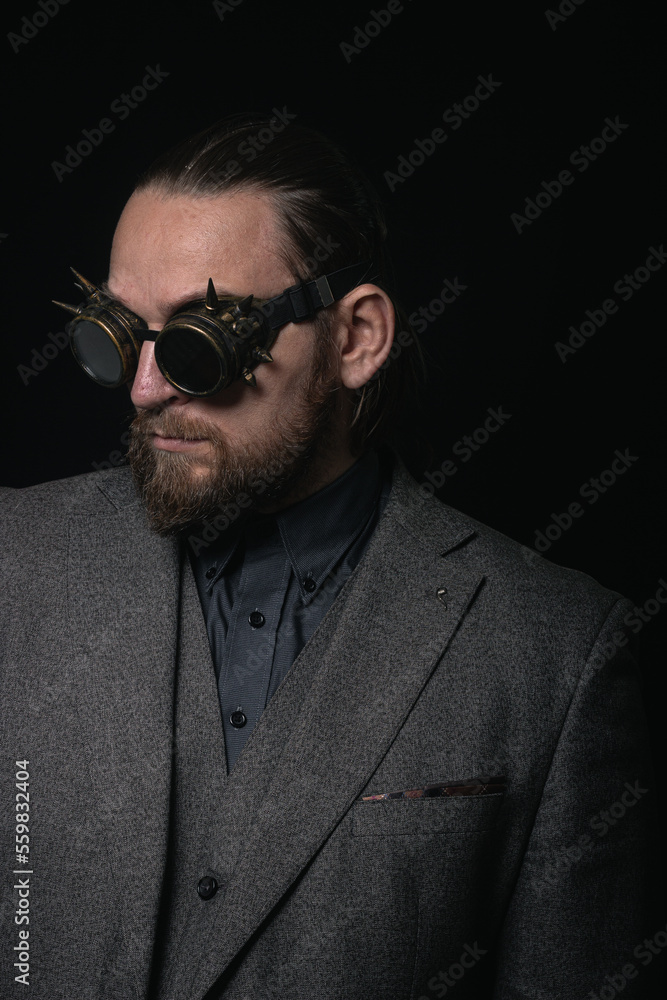 Obraz premium charismatic man in a classic suit and steampunk goggles on a black background stylish Portrait