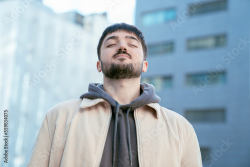 Positive young man inhaling fresh air outside