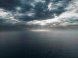 Aerial photo of a cloudy sky with sunbeams filtering and illuminating the surface of the calm sea of Palinuro. Photos of the Campania coast (southern Italy)