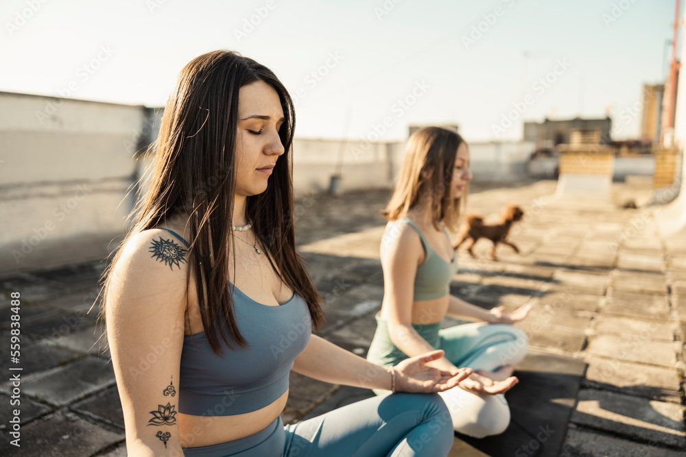Two Woman Doing Yoga Outdoors On A Rooftop Terrace