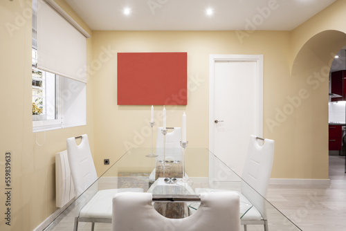 Living room with glass table  chairs upholstered in white skay and window with blind