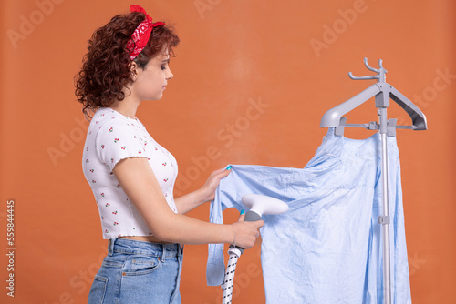 Steamer for ironing shirts and other clothing. Girl with curly hair. photo