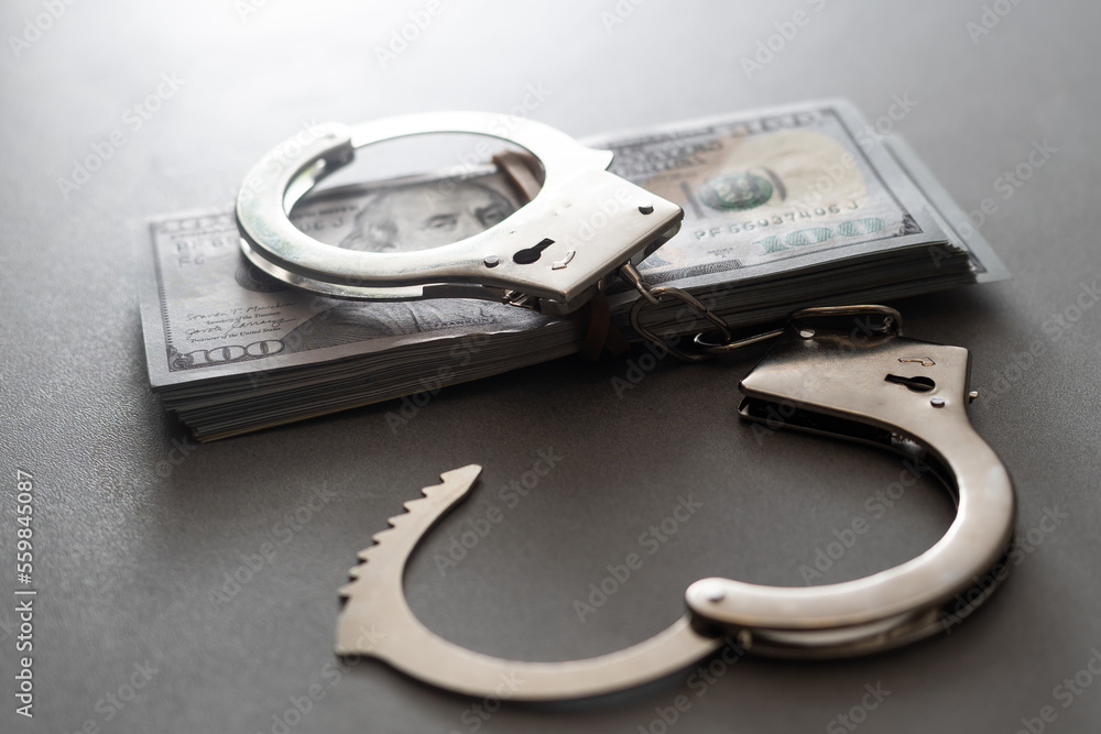 handcuffs and one hundred dollars on the wooden table handcuffs and one hundred dollars on the wooden table