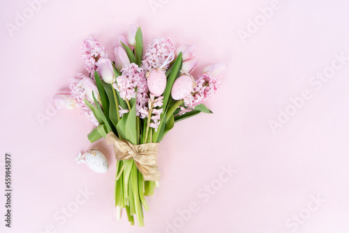 Easter scene with fresh tulips and hyacinth flowers over pink background, scene with easter colored eggs
