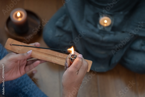 Crop woman lightening incense stick during worship photo