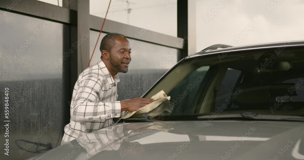 Black man wiping his washed car at the car wash Black man wiping his washed car at the car wash