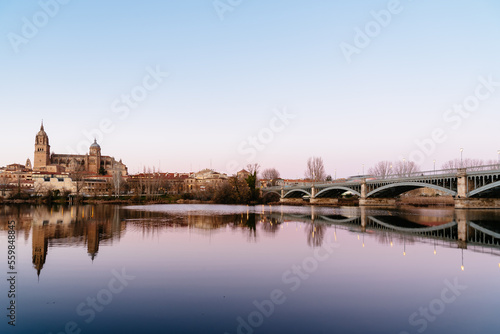 Scenic view of Salamanca with the Cathedral and iron bridge reflected in the Tormes River at sunset. Castilla Leon, Spain