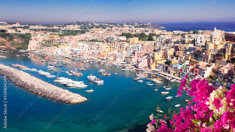view of Procida island colorful town with small harbour from above with flowers, Italy, web banner format