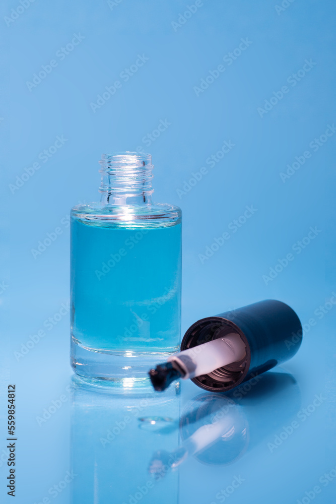 Transparent nail polish stands on a blue background. Beauty products. Transparent nail polish stands on a blue background. Beauty products.