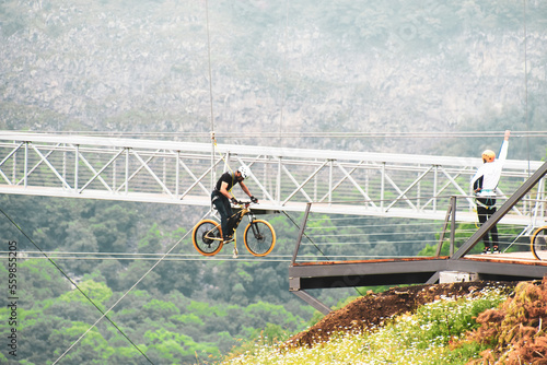 Dashbashi, Georgia- 19th JUne, 2022: man pedal zip bike over valley in beautiful caucasus mountains photo