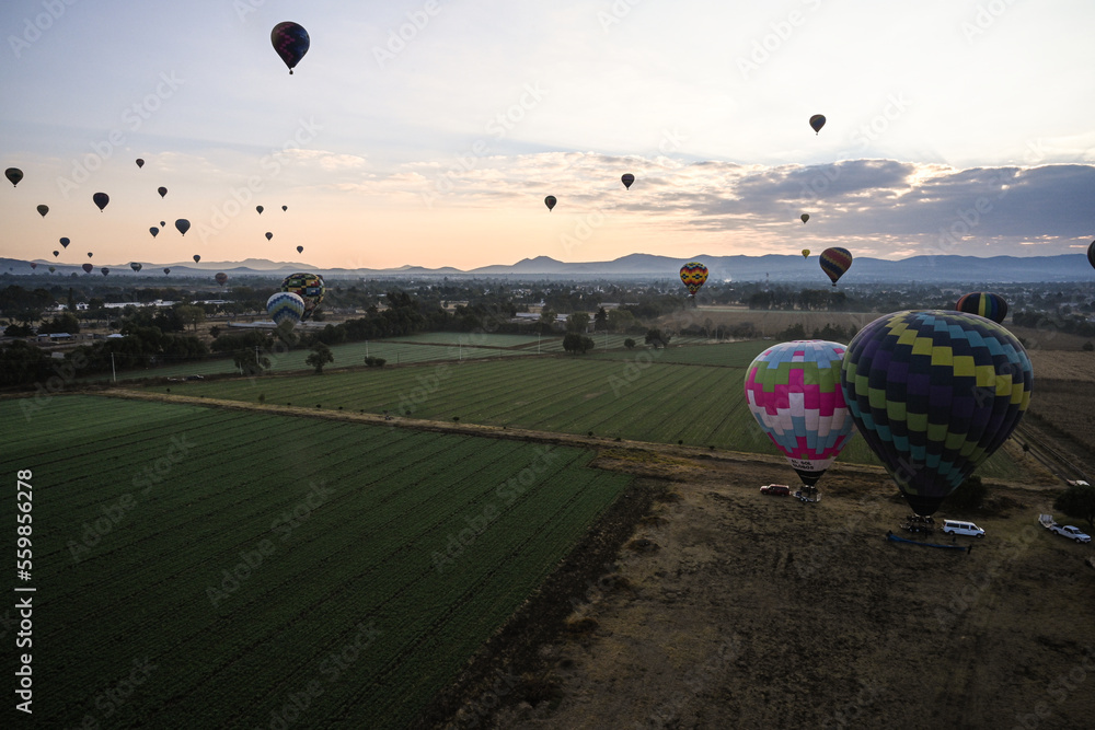 Obraz premium Landscape of sunrise with hot air balloons rising over fields and ancient teotihuacán ruins outside of Mexico City