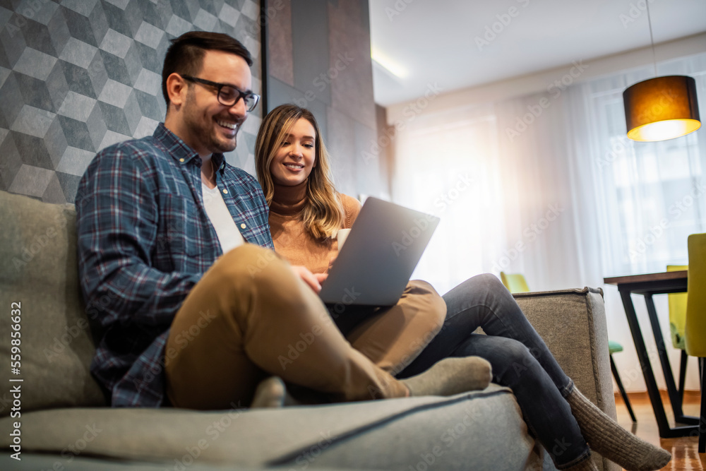 Couple using laptop in living room at home Couple using laptop in living room at home