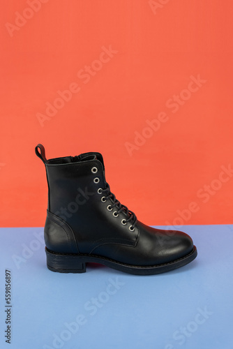Woman black boot on a orange and blue background. Side View. Copy Space.