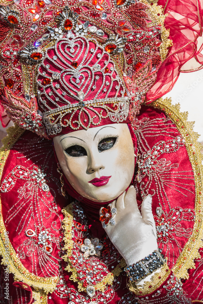 ritratto di maschera elaborata al carnevale di venizia, colore rosso, tiara e collare, mano con guanto portata alla gola, anello sopra il guanto ritratto di maschera elaborata al carnevale di venizia, colore rosso, tiara e collare, mano con guanto portata alla gola, anello sopra il guanto