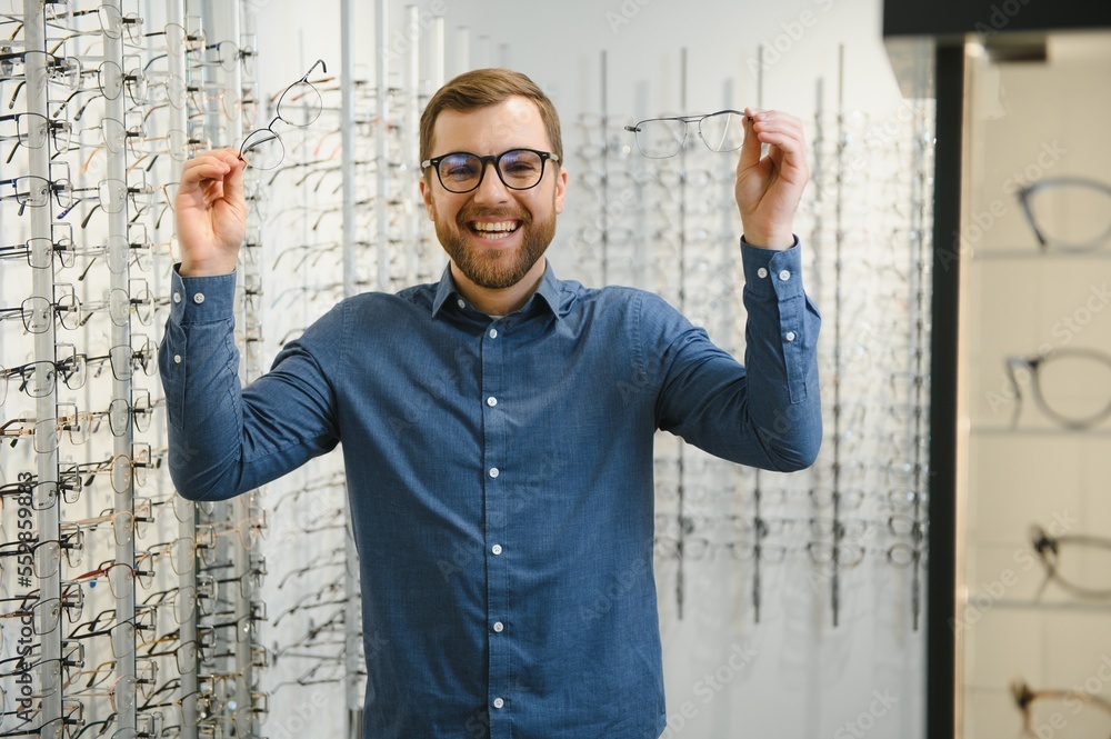 Naklejka premium male client chooing new eyeglasses frame for his new eyeglasses in optical store