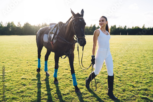 Photos Young horsewoman walking across field with horse