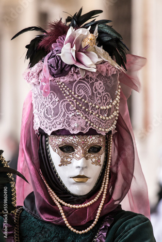 ritratto verticale di una persona in maschera al carnevale di venezia, cappello con piume e perle pendenti photo