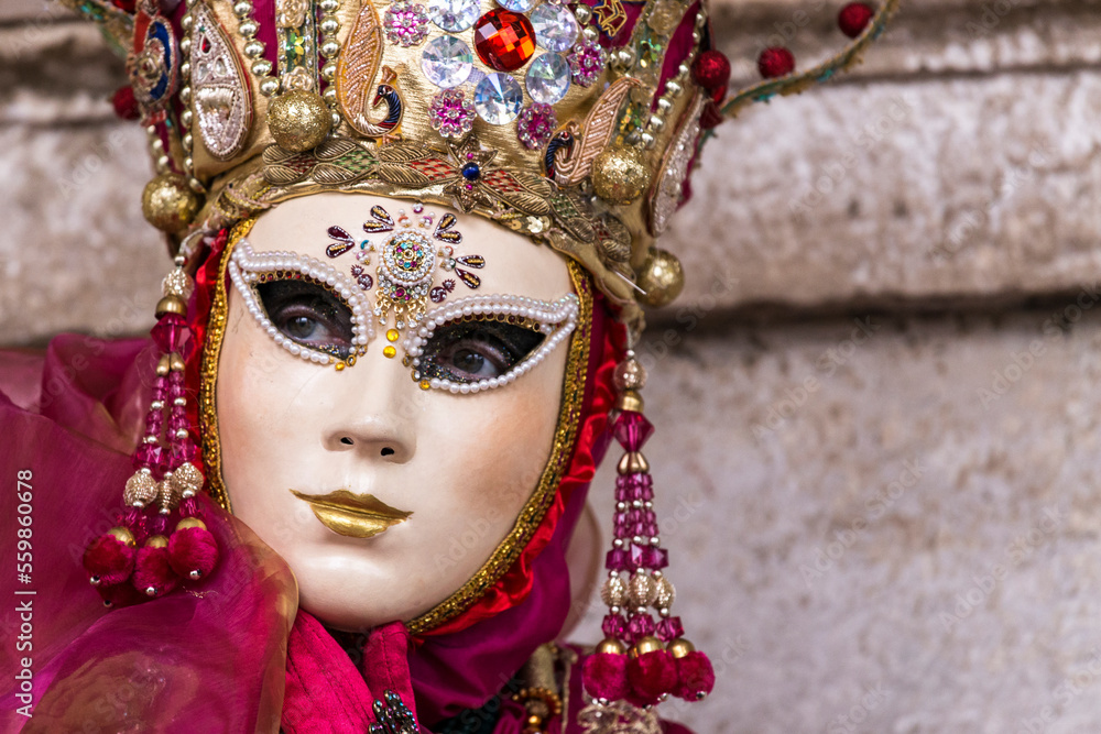 ritratto orizzontale di una maschera al carnevale di venezia, maschera con corona e pendagli, colori rossi.