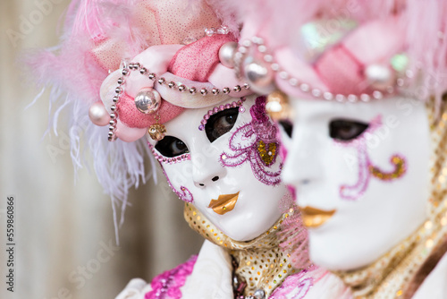 Fototapeta Naklejka Na Ścianę i Meble -  coppia di maschere al carnevale di venezia, primo piano sui volti, tonalità rosa, maschera che guarda in camera