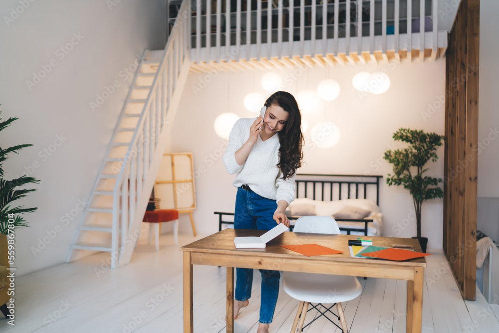 Cheerful woman reading book while talking on phone Cheerful woman reading book while talking on phone