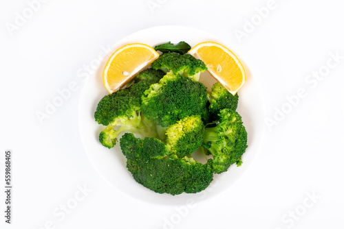 Boiled broccoli with lemon in a plate. Isolated on white background. Top view