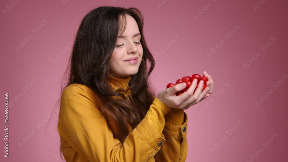 Portrait of a smiling woman holding tasty cherry tomatoes. Close-up view of a cute, healthy female enjoying delicious food. High quality 4k footage Portrait of a smiling woman holding tasty cherry tomatoes. Close-up view of a cute, healthy female enjoying delicious food. High quality 4k footage