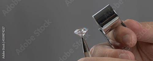 Foto Diamond dealer evaluates the quality of round cut diamond through magnifying glass