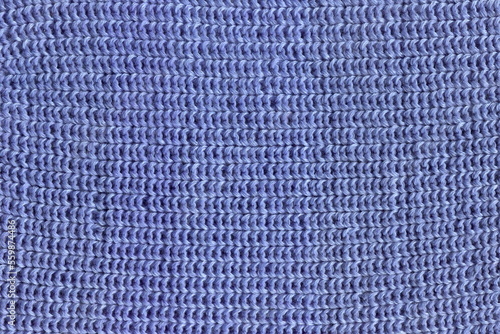 The texture of a hand-knitted natural woolen cloth with an English elastic band of blue color. A warm, winter woolen jacket. Close-up knitting, close-up loops.