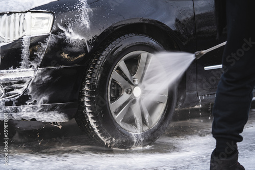 the car at the car wash is covered with foam, wash under pressure with a stream of water