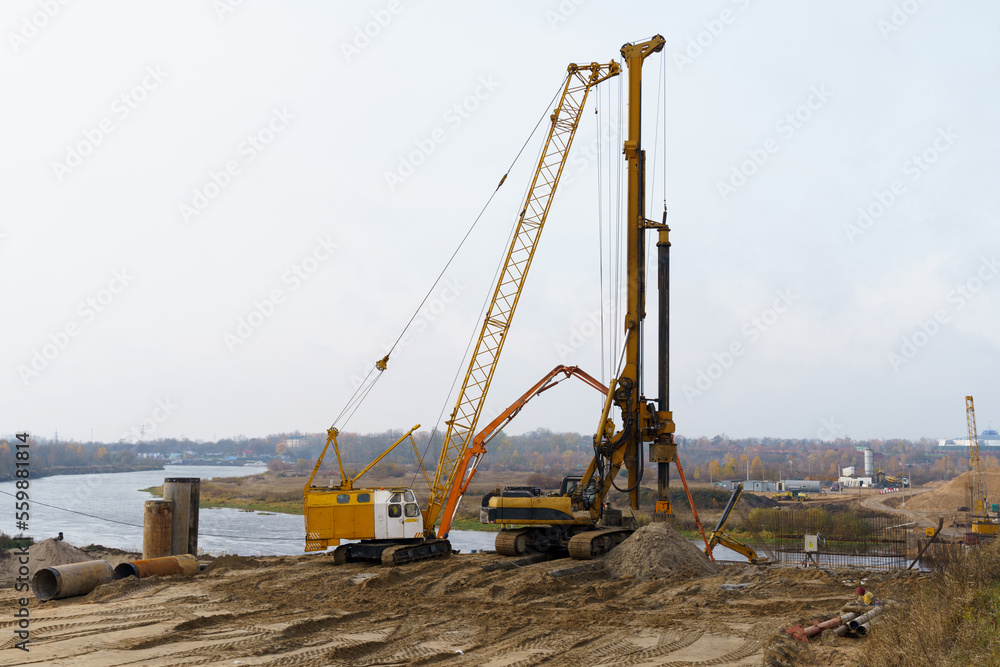 The work of cranes and other equipment at the construction site of the bridge across the river The work of cranes and other equipment at the construction site of the bridge across the river