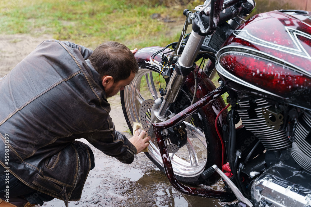 Washing a motorcycle engine with a detergent using a sponge.