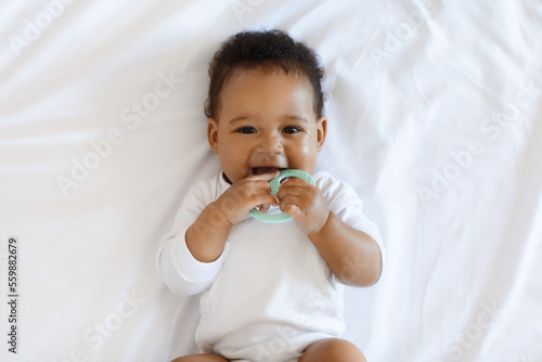 Obraz na plátne Portrait Of Adorable African American Baby Biting Teether And Looking At Camera