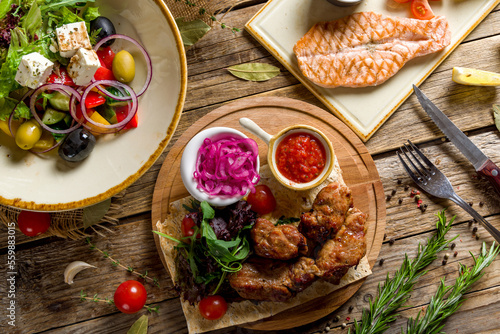 Kebab of pork with red onion and tomato sauce on wooden table top view