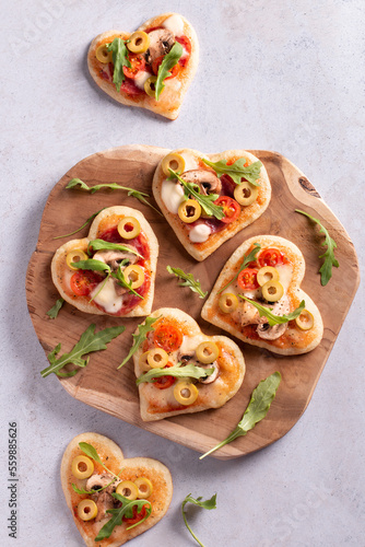 Heart shape mini pizzas on wooden board for Valentines day holiday, top view