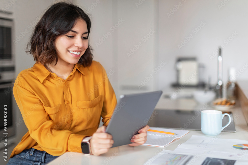 Remote Education. Smiling Young Arab Woman Study With Digital Tablet In Kitchen Remote Education. Smiling Young Arab Woman Study With Digital Tablet In Kitchen