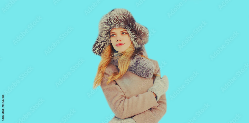 Obraz premium Portrait of beautiful young blonde woman in winter hat on blue background