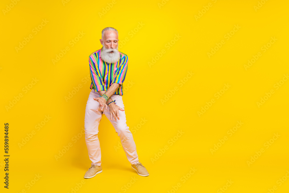 Full length photo of excited cheerful man wear colorful shirt having fun empty space isolated yellow color background Full length photo of excited cheerful man wear colorful shirt having fun empty space isolated yellow color background